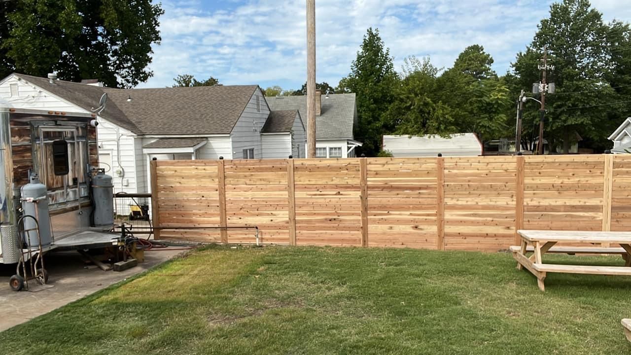 Backyard with wooden privacy fence, lawn, picnic table, and RV parked beside a house