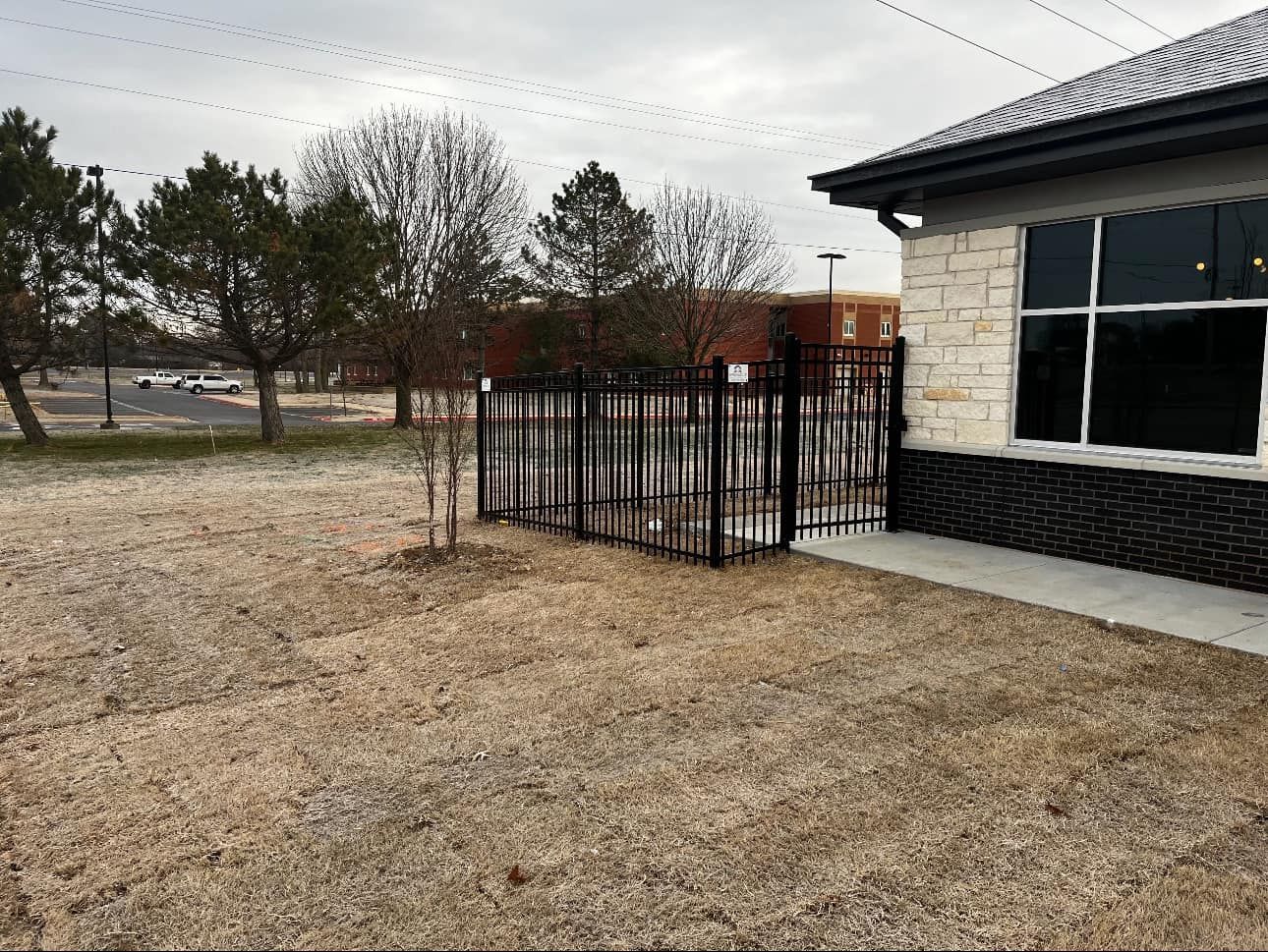 Empty fenced patio beside a stone building on a cloudy day