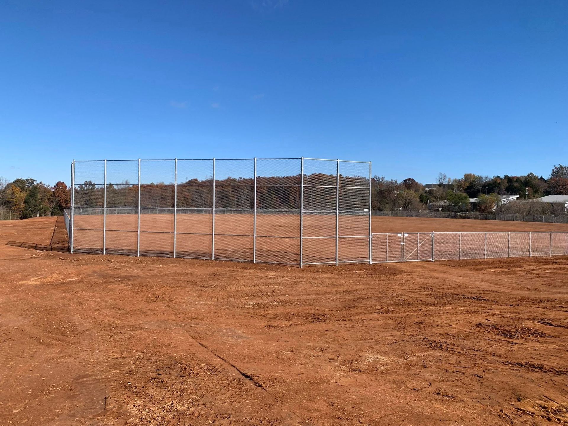 Baseball field with a dirt infield, chain-link backstop, and blue sky
