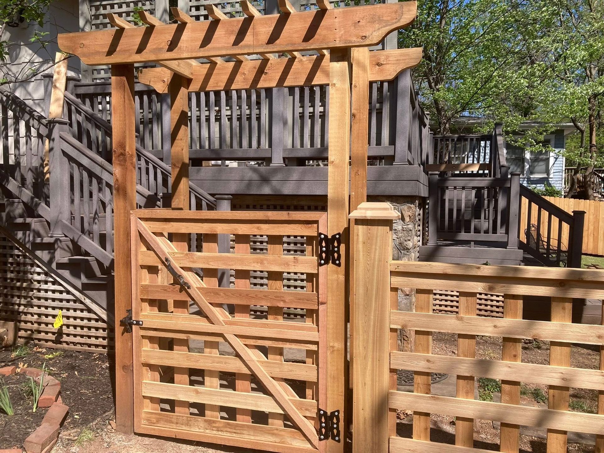 Wooden garden gate with lattice panels and pergola entrance in a residential yard