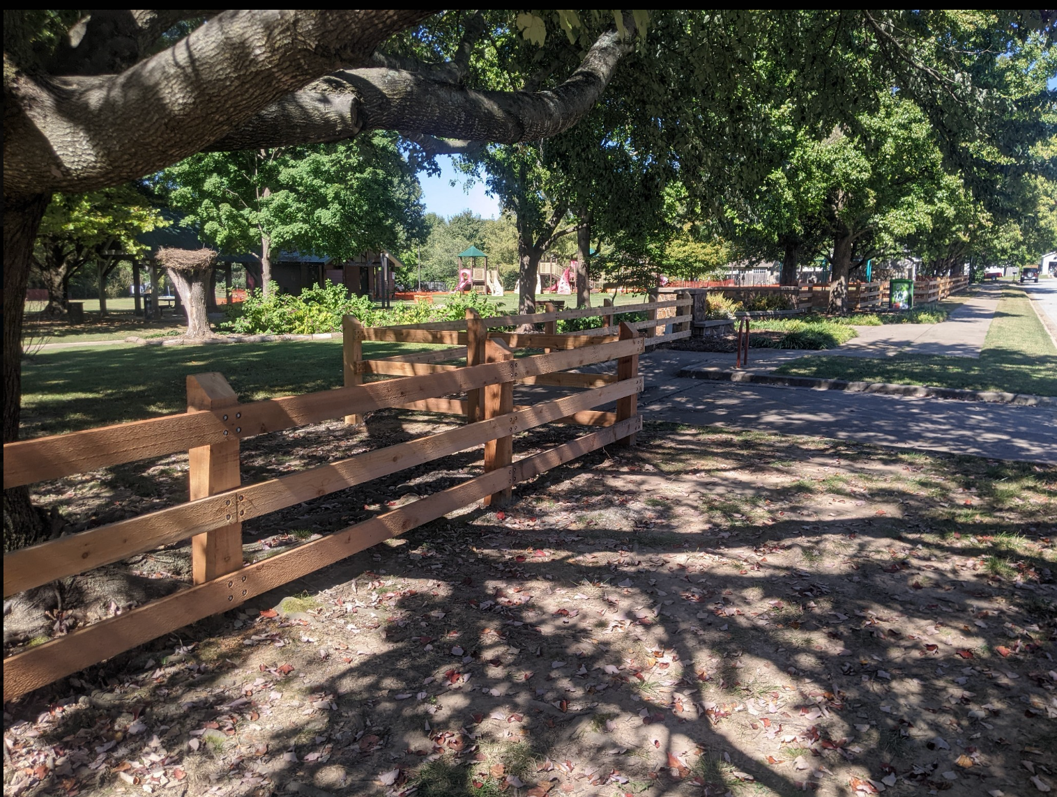 Wooden fence and gate beside apartment buildings, with stairs and a dirt path in a courtyard.