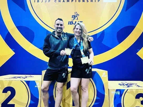 A man and a woman standing on a podium with the number 2 and 3 behind them