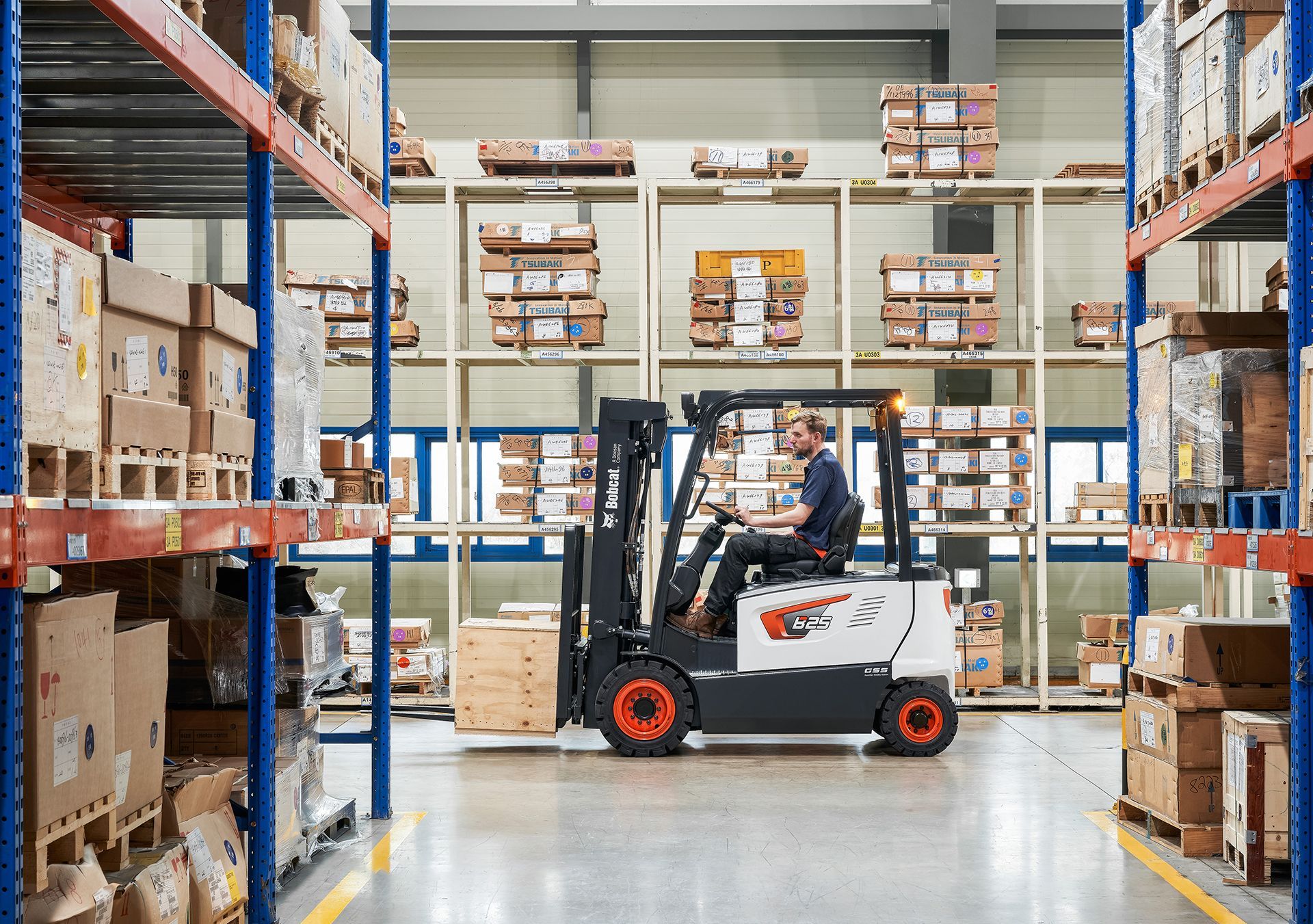 A man is driving a forklift in a large warehouse.