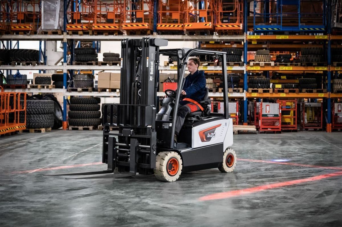 A man is driving a forklift in a warehouse.