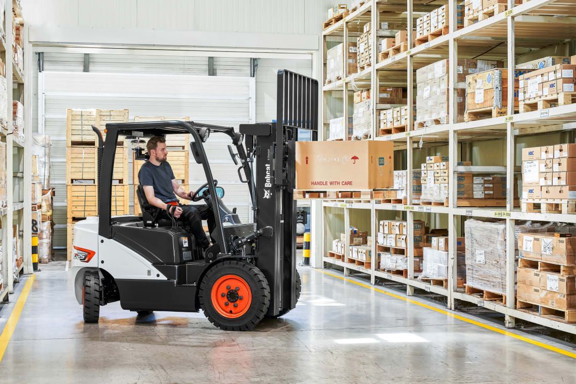 A man is driving a forklift in a warehouse.