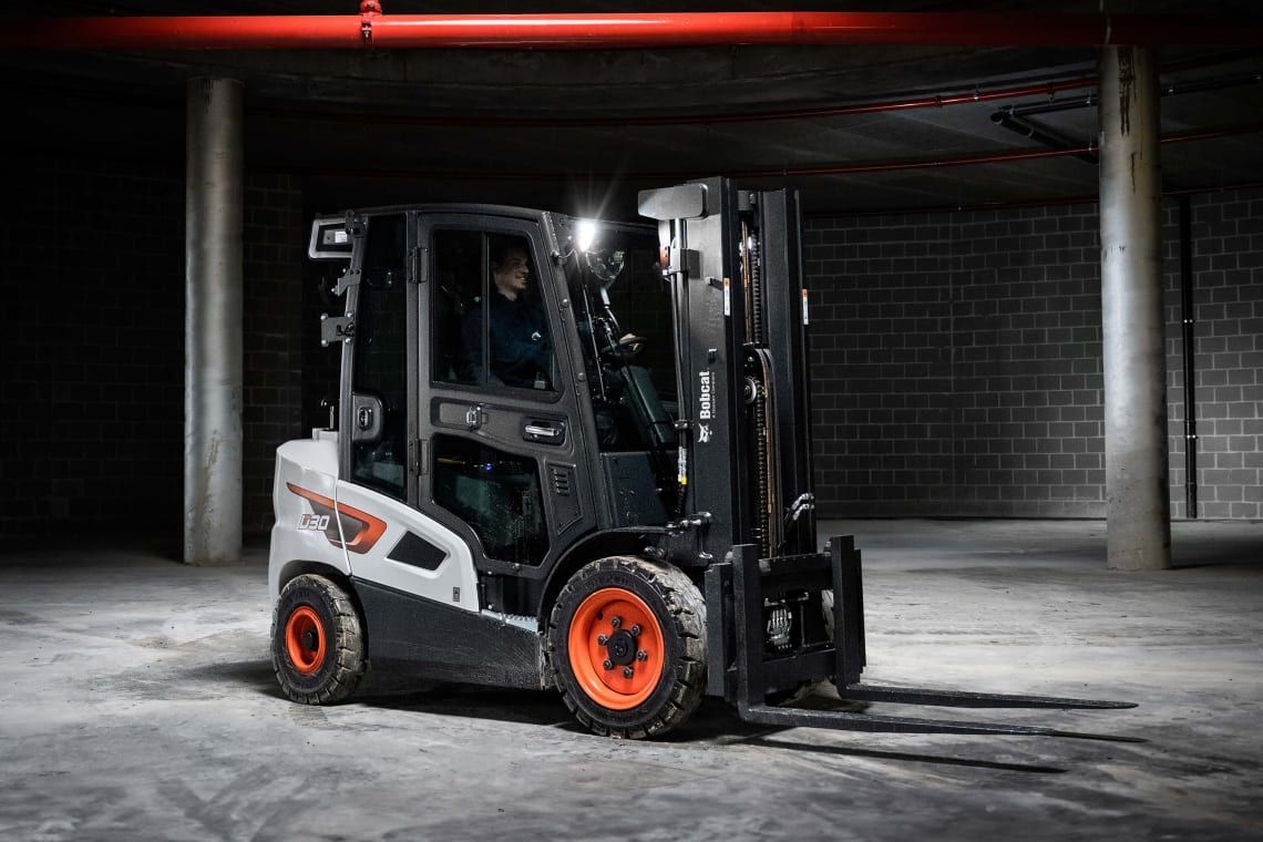 A man is driving a forklift in a parking garage.