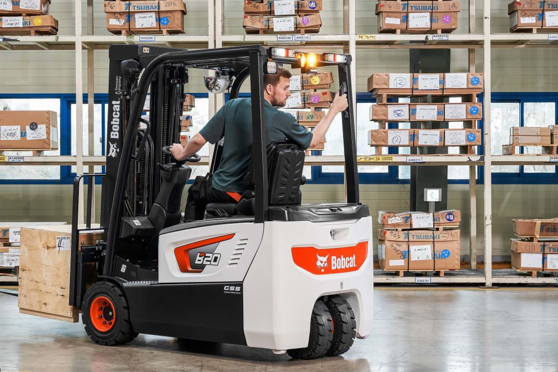 A man is driving a forklift in a warehouse.