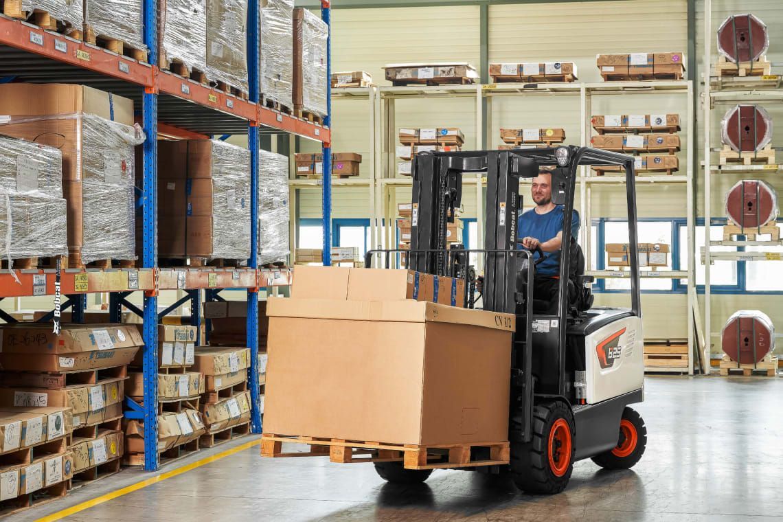 A man is driving a forklift in a warehouse.