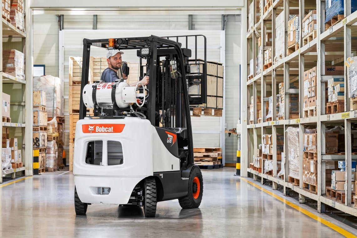 A man is driving a forklift in a warehouse.