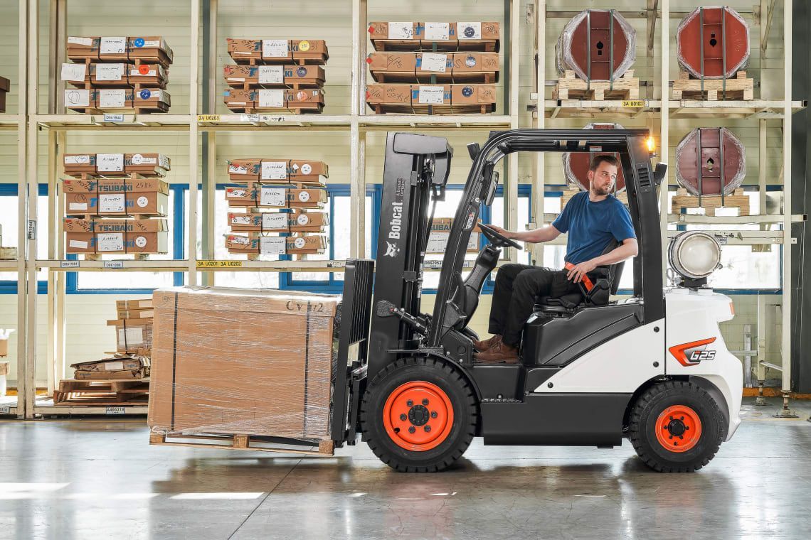 A man is driving a forklift in a warehouse.