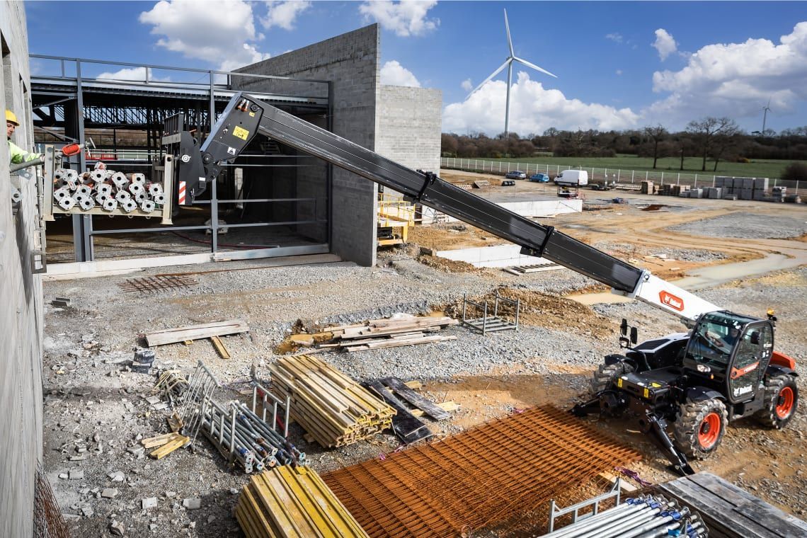 A construction site with a crane and a windmill in the background.