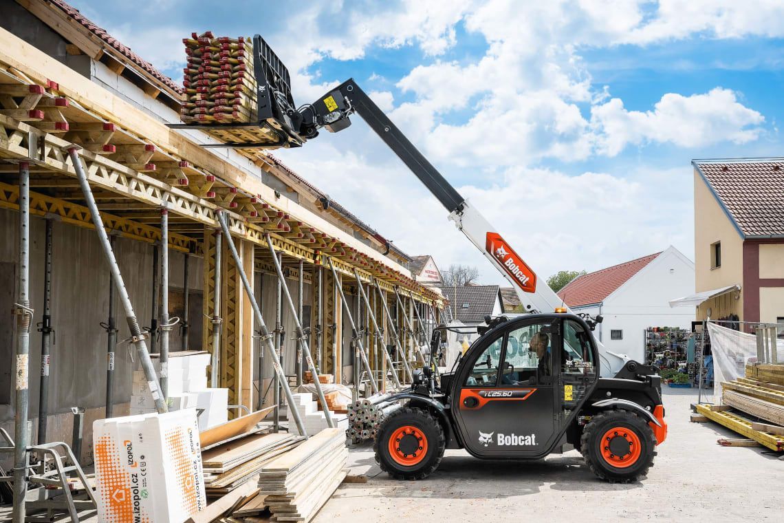 A forklift is lifting a pallet of wood on top of a building under construction.