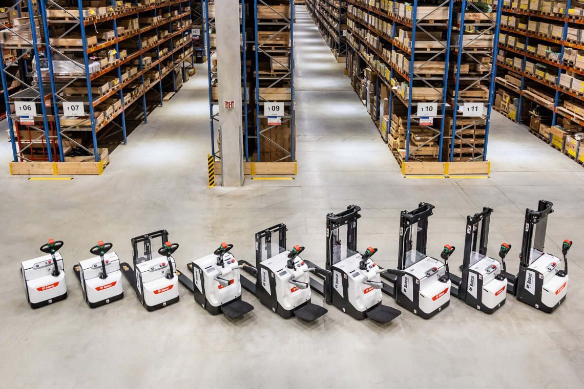 A row of forklifts are lined up in a warehouse.