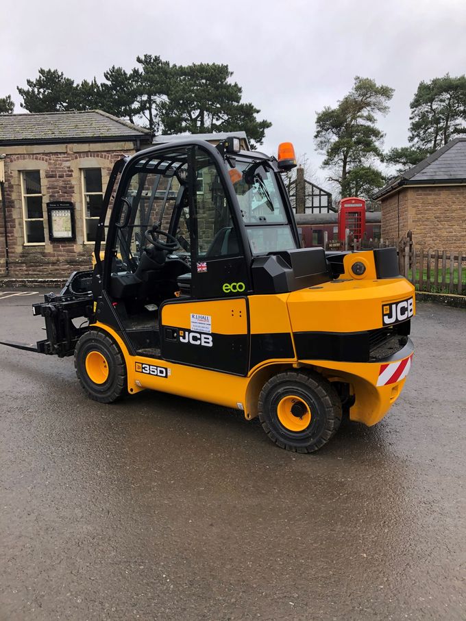 A yellow and black forklift is parked in front of a building.