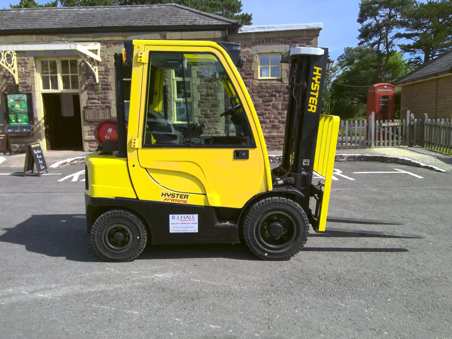 A yellow hyster forklift is parked in front of a building