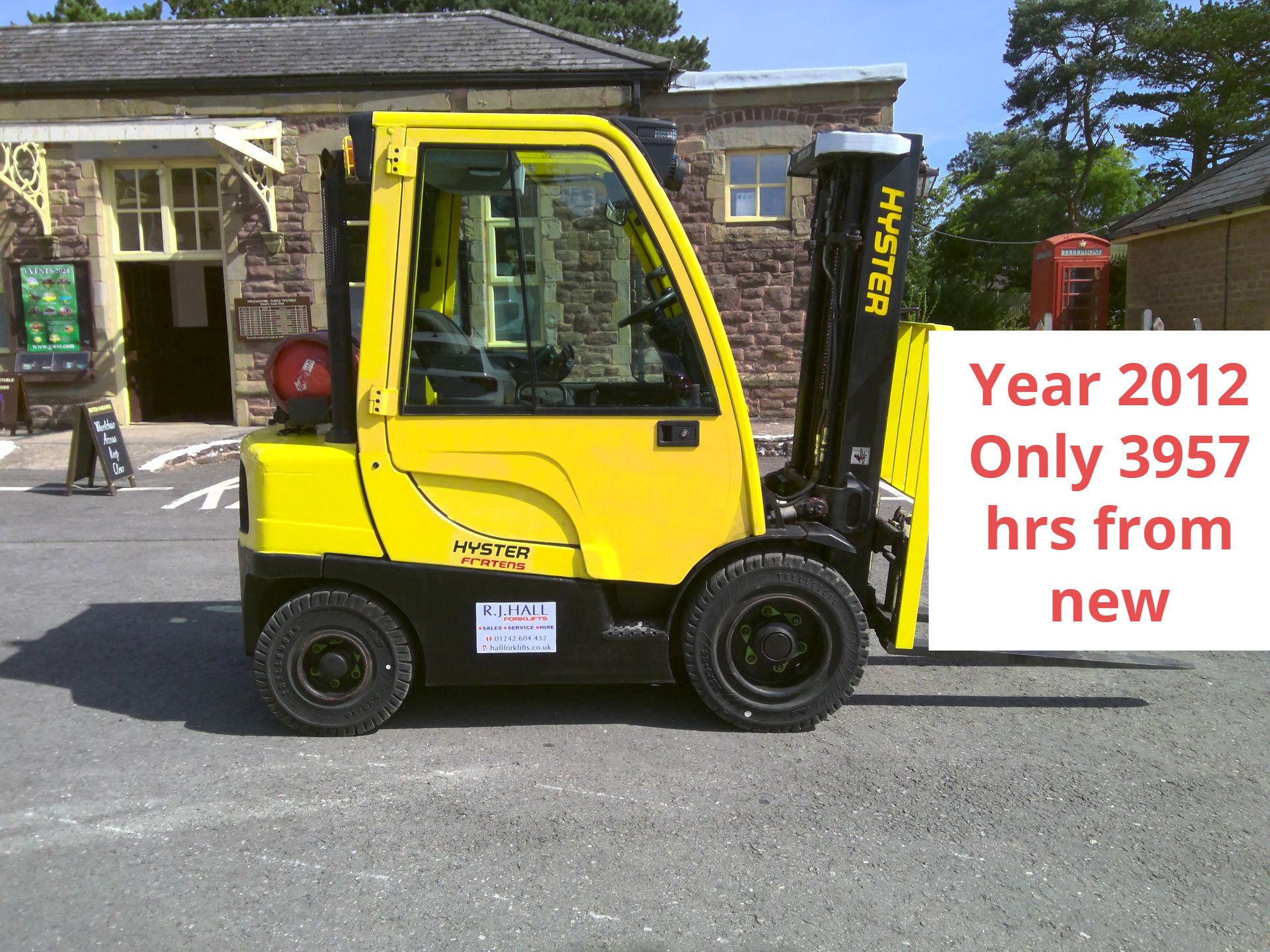 A yellow hyster forklift is parked in front of a building