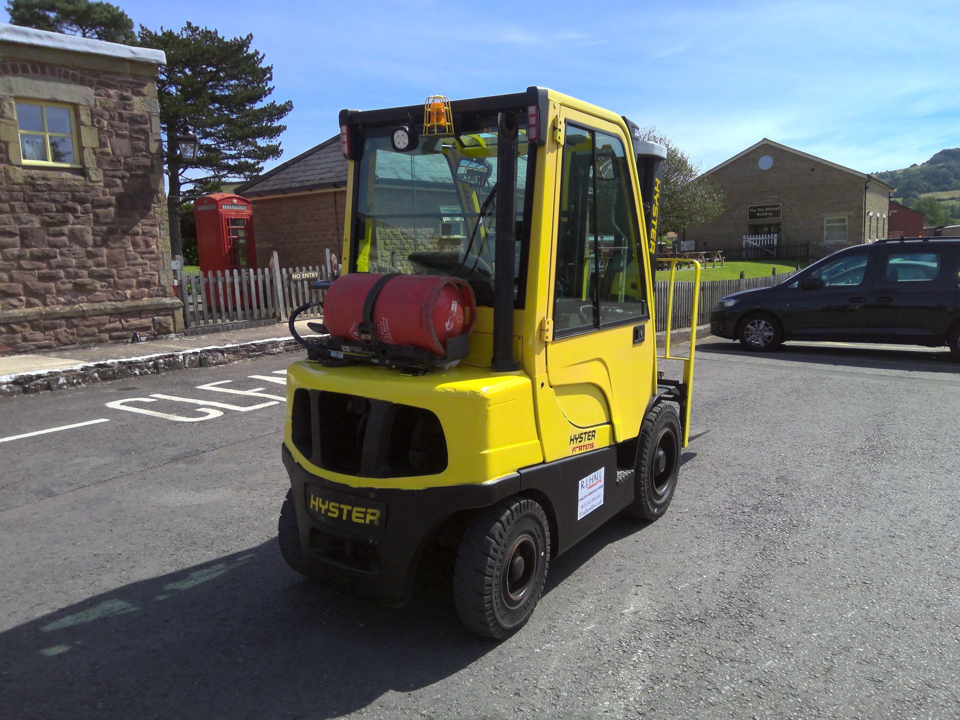 A yellow hyster forklift is parked in a parking lot