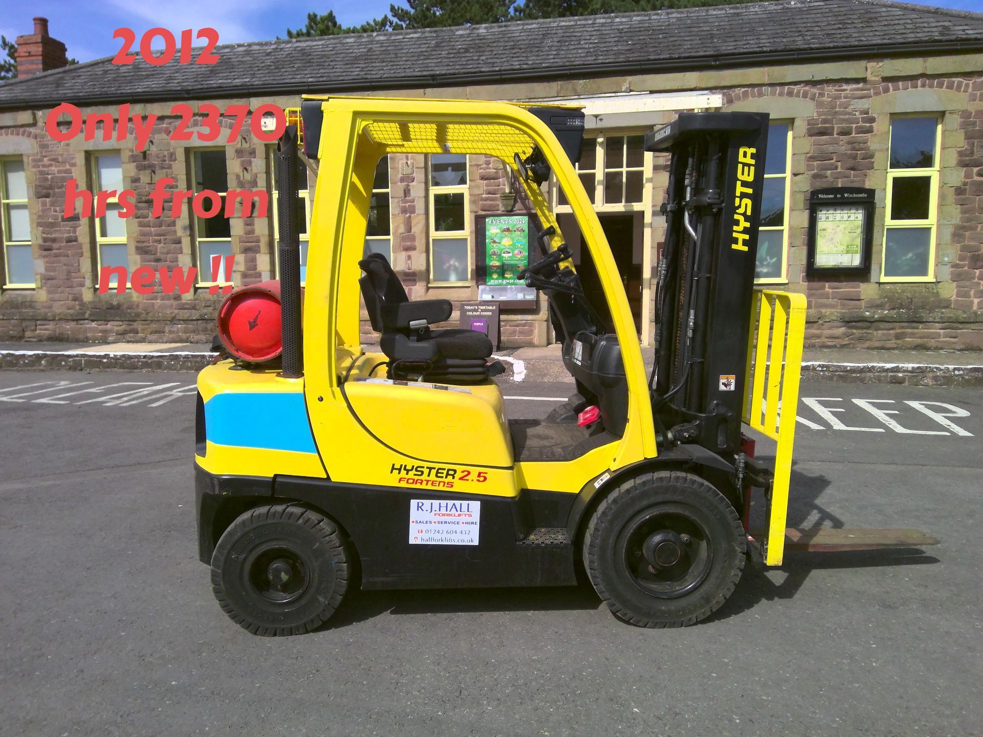 A yellow hyster forklift is parked in front of a building