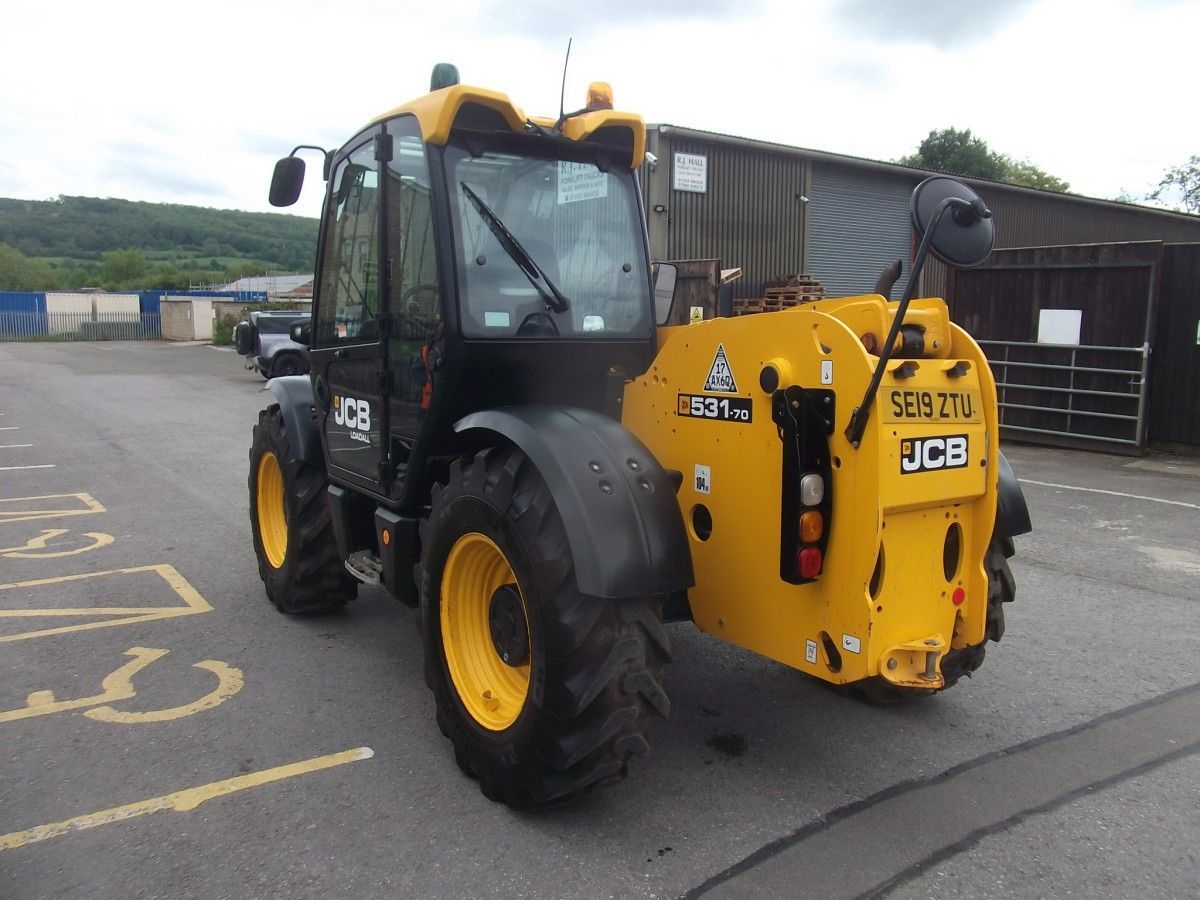 A yellow and black jcb tractor is parked in a parking lot