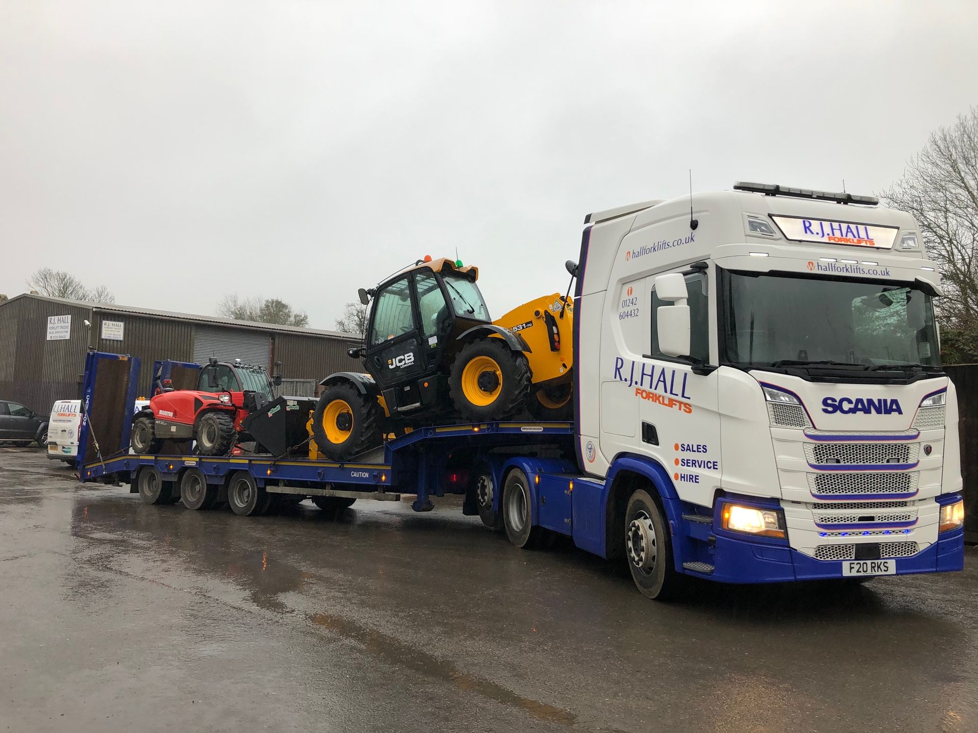 A truck is carrying a tractor on a trailer.