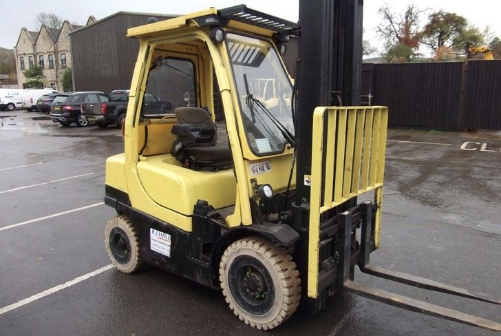 A yellow forklift is parked in a parking lot.