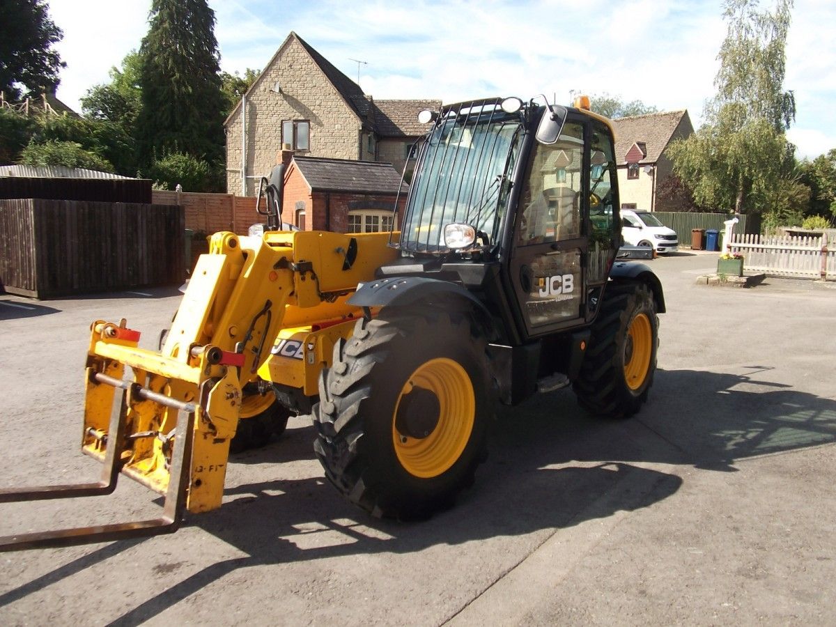 A yellow and black jcb tractor is parked in a parking lot