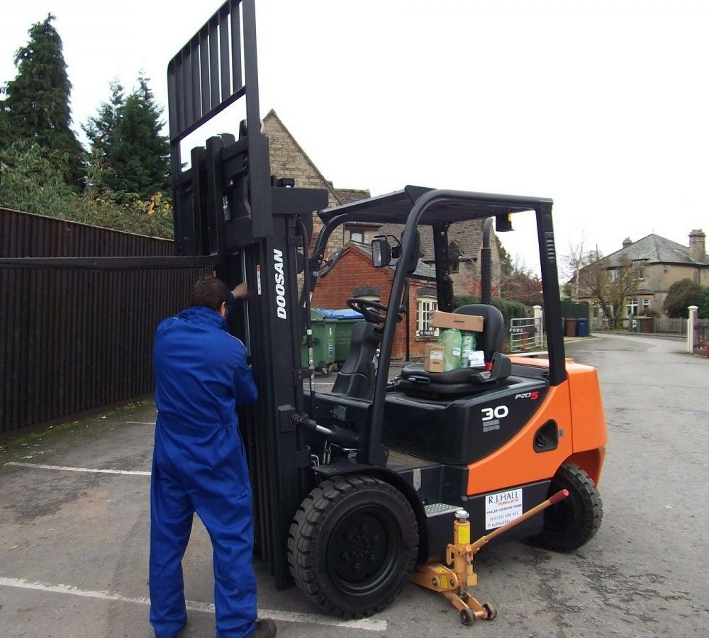 Forklift technician performing routine maintenance on a forklift truck inside a UK warehouse, highlighting RJ Hall Forklifts' professional servicing and safety standards.