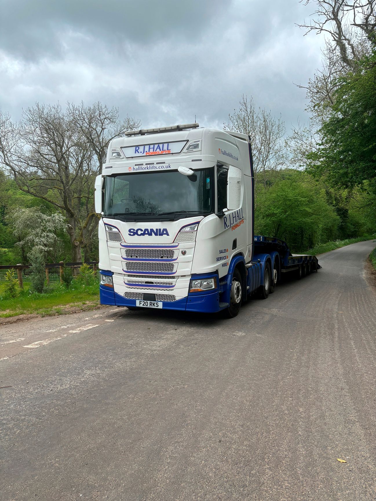 A blue and white truck is parked on the side of a road.