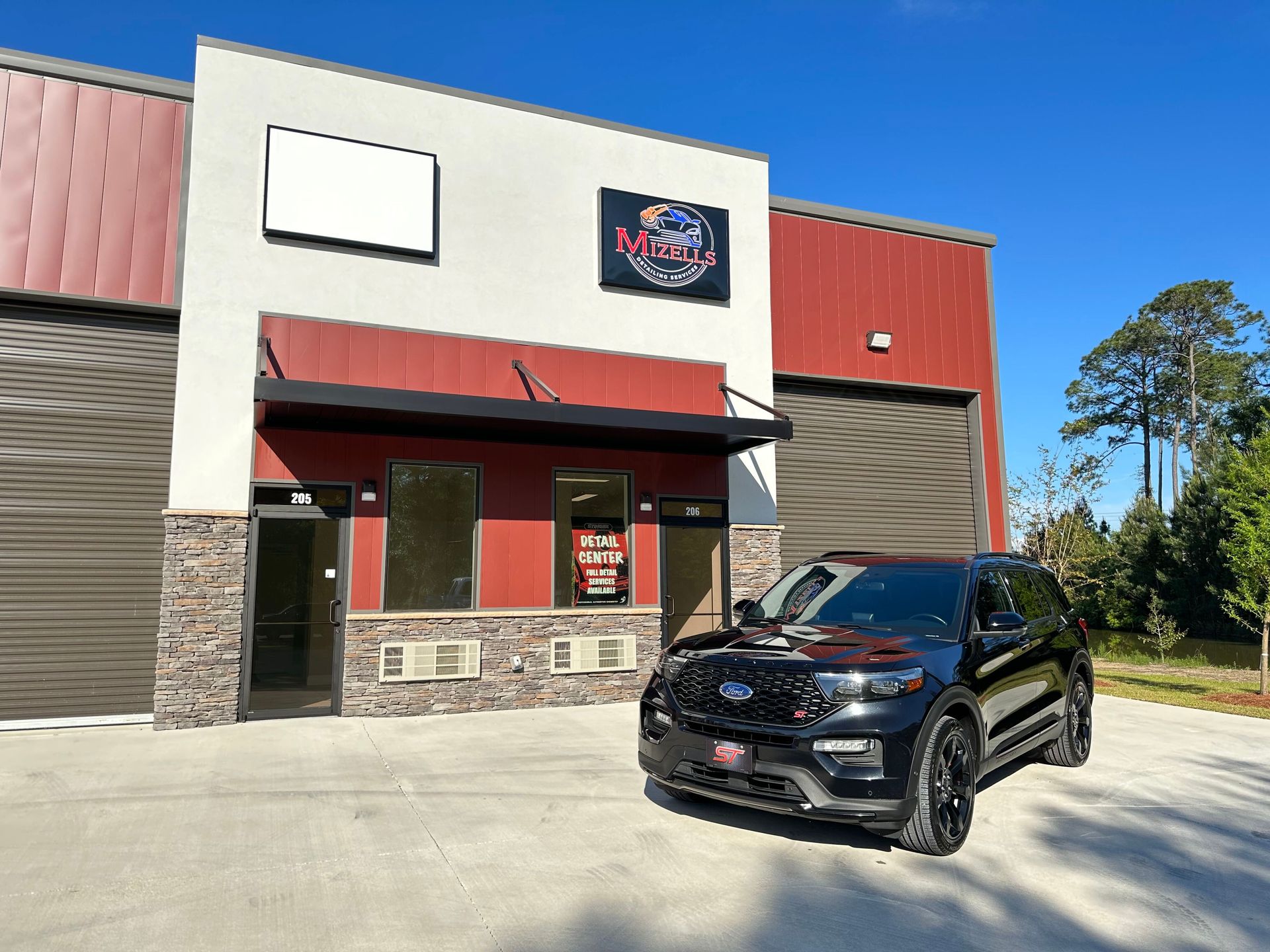 Black SUV parked outside a red and white storefront on a sunny day