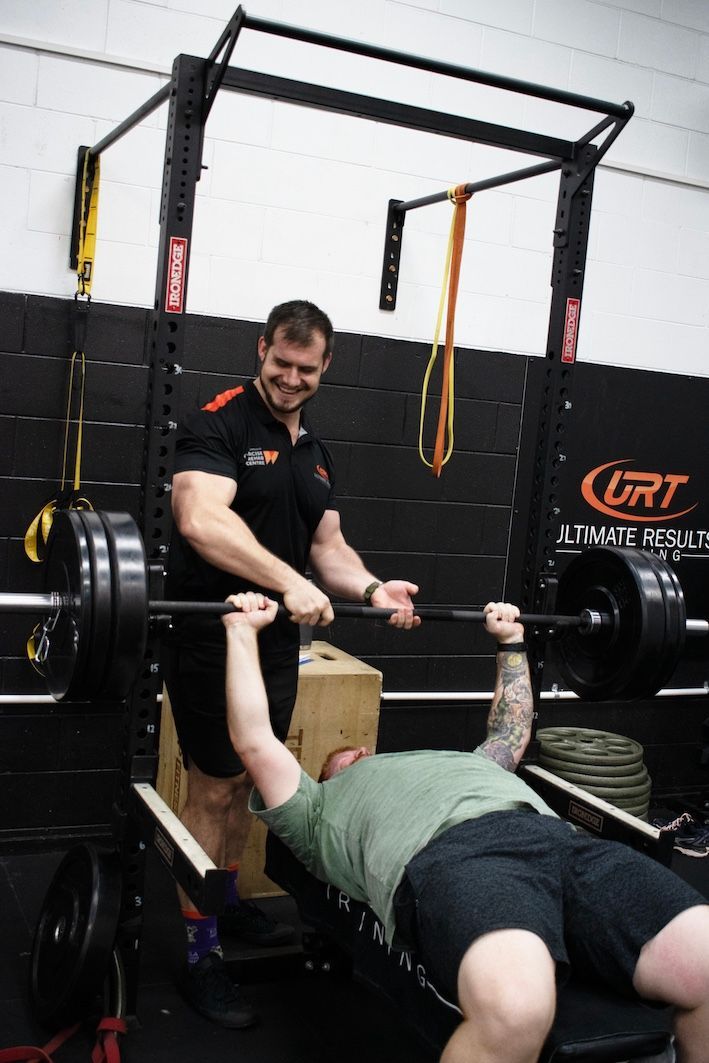 Personal Trainer Assisting Man Doing Bench Press — Ultimate Results Training in Aitkenvale, QLD