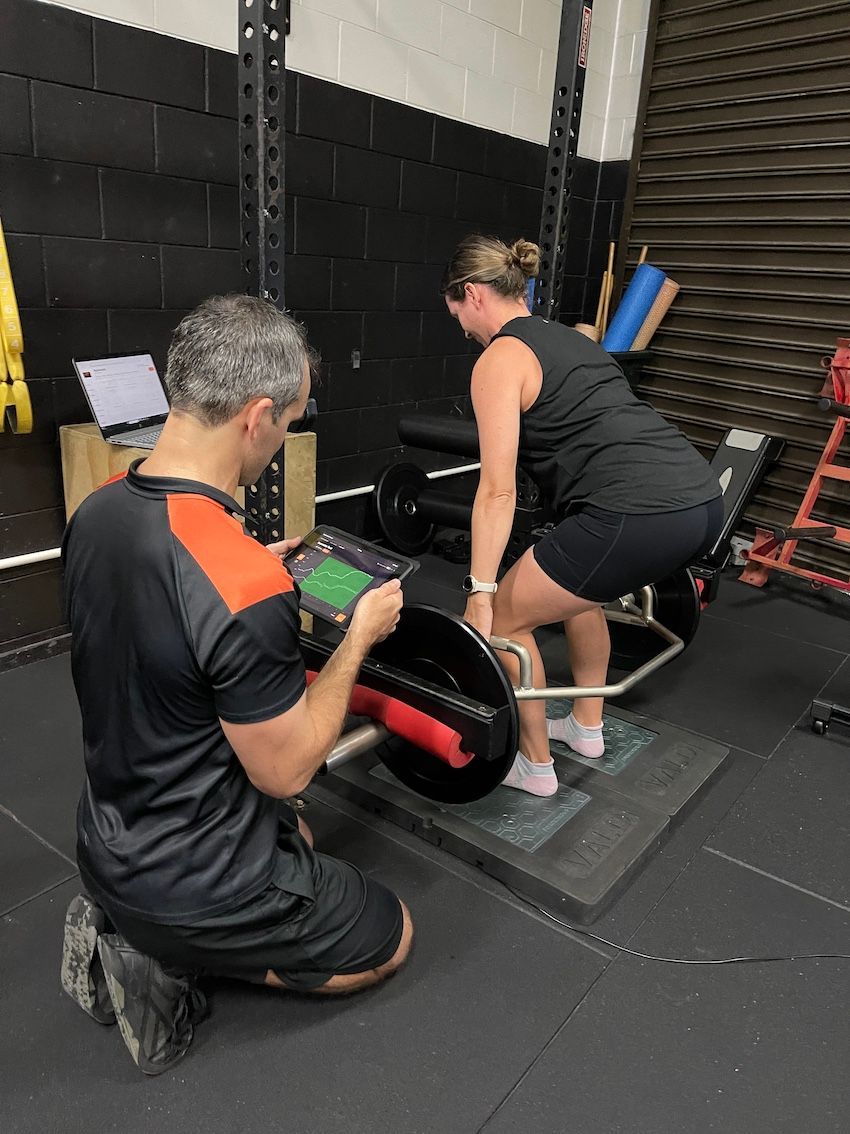 Trainer Holding Tablet Whilst Lady Lifts In Physiotherapy Session — Ultimate Results Training in Aitkenvale, QLD