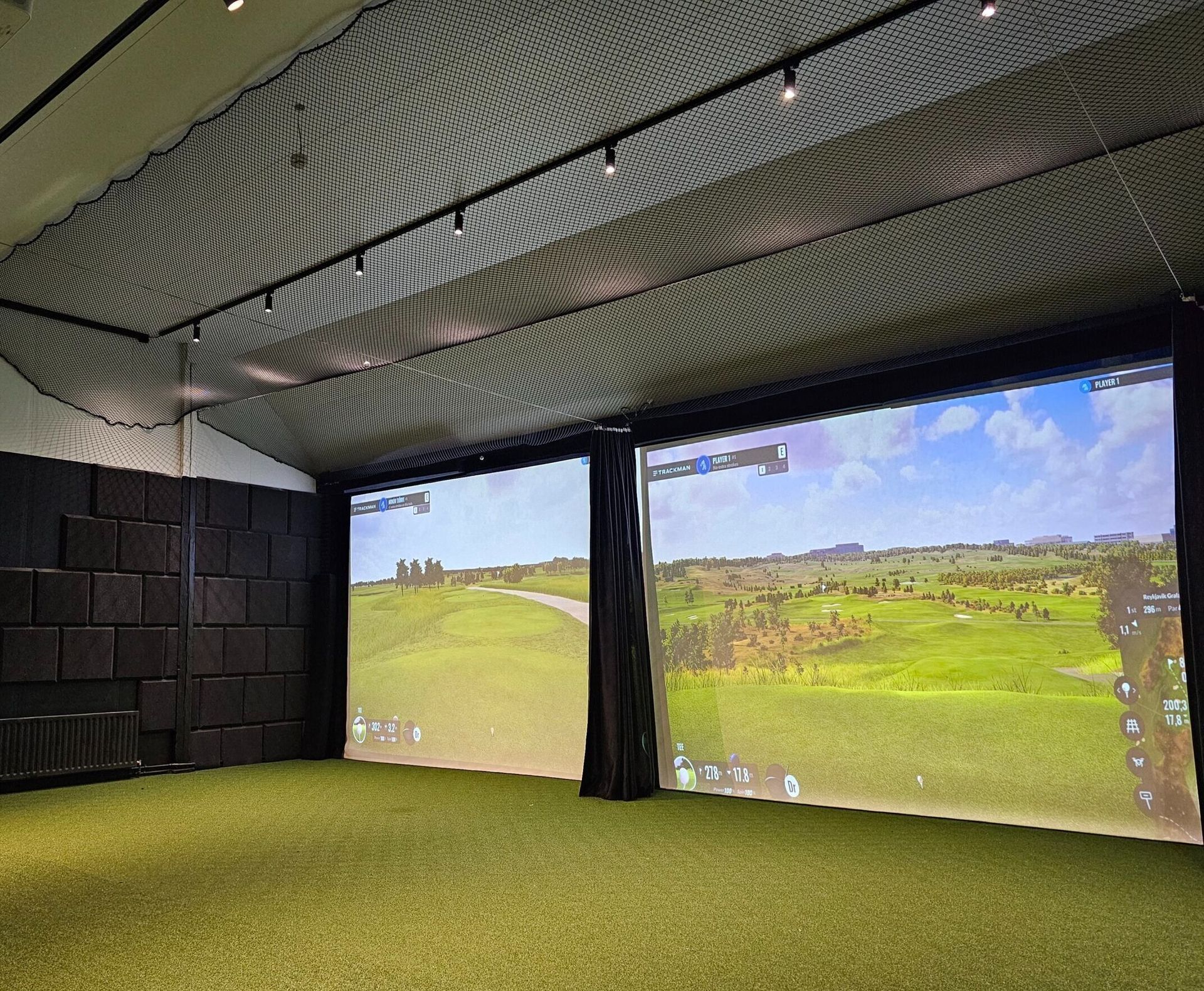 Innanhúss golfhermir með tveimur stórum skjávarpa sem sýna grænan völl og fairway.