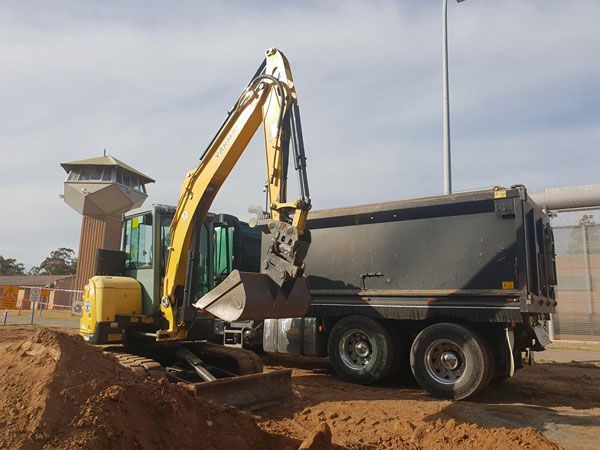 An excavator is loading dirt into a dump truck