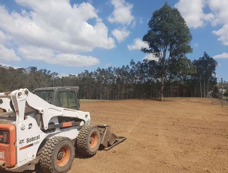 A bobcat skid steer is parked in a dirt field.