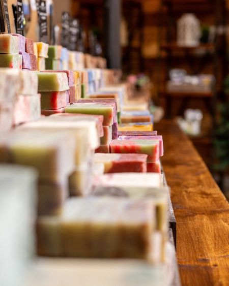 Rows of colorful soap bars lined up on a wooden shelf in a shop