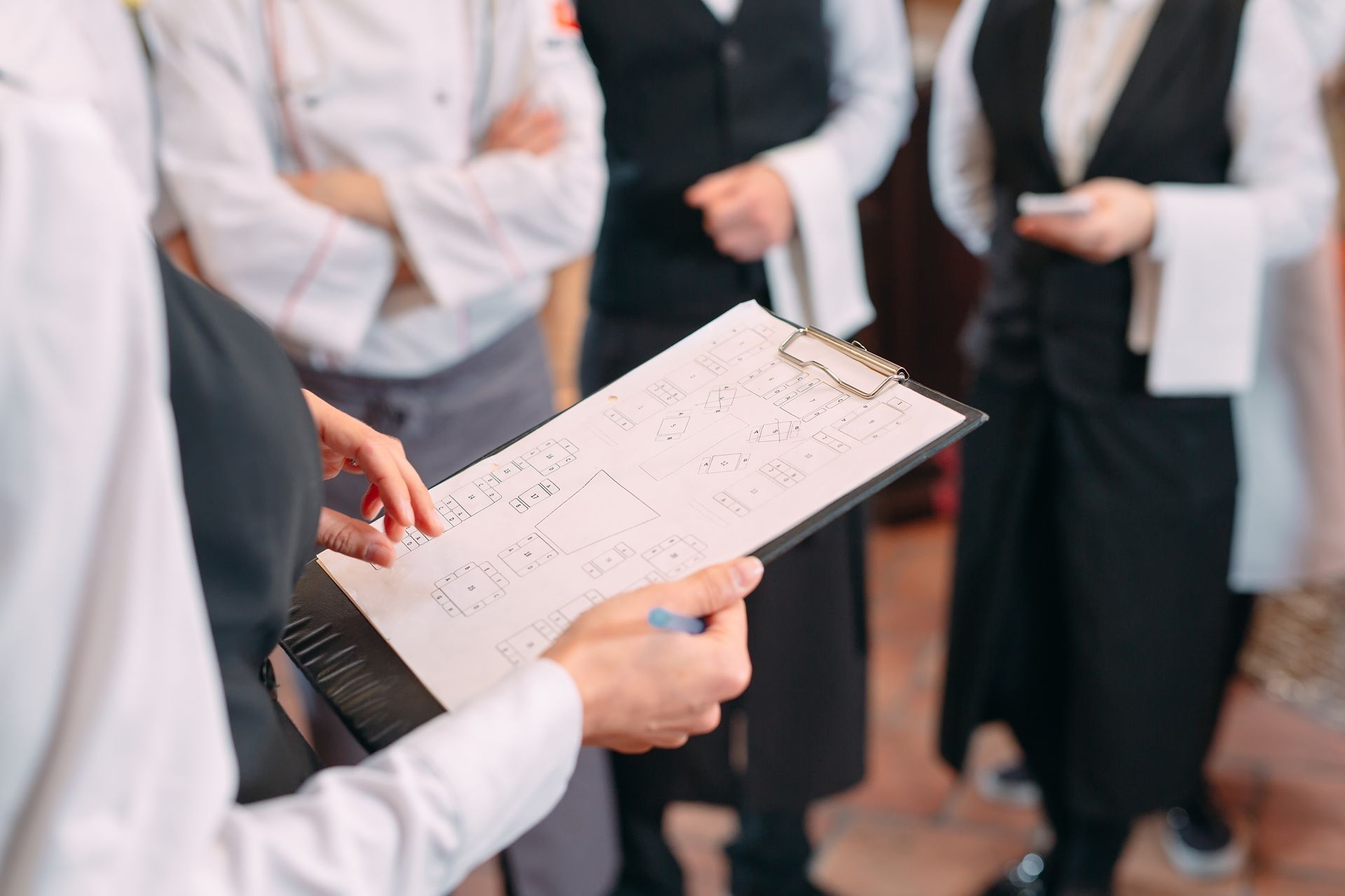 Person holding a clipboard during a meeting with others in white lab coats