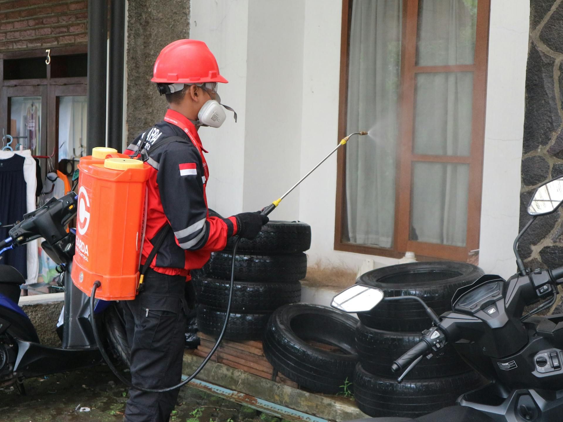 A man is spraying tires with a sprayer in front of a house.