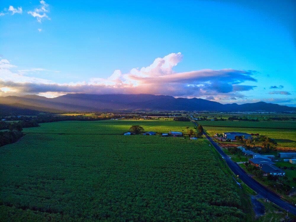 An Aerial View of a Lush Green Field With Mountains in the Background at Sunset — FNQ Drilling in Tully, QLD