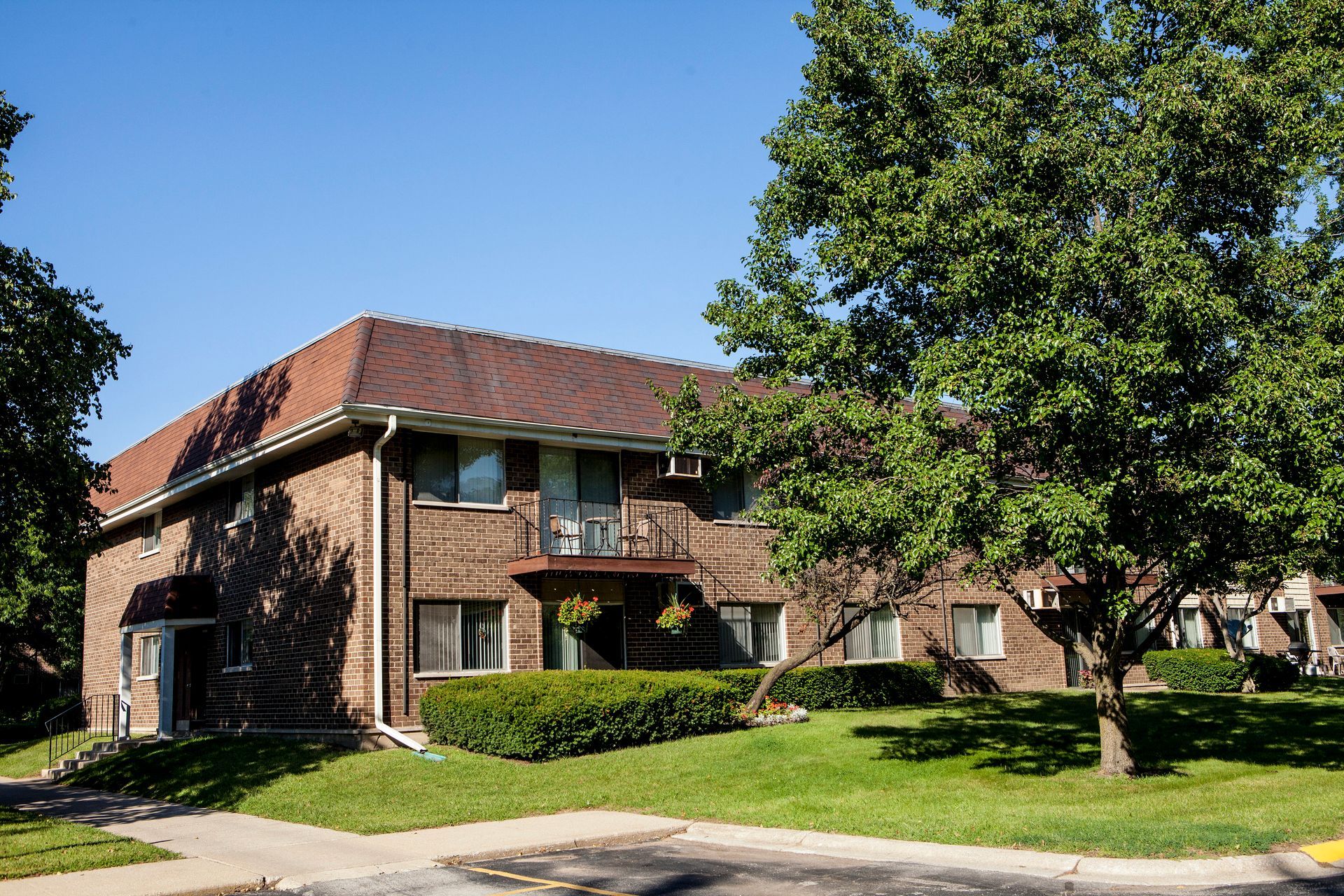 Sign for Arbor Glen apartment complex with flags, greenery, and buildings in the background.