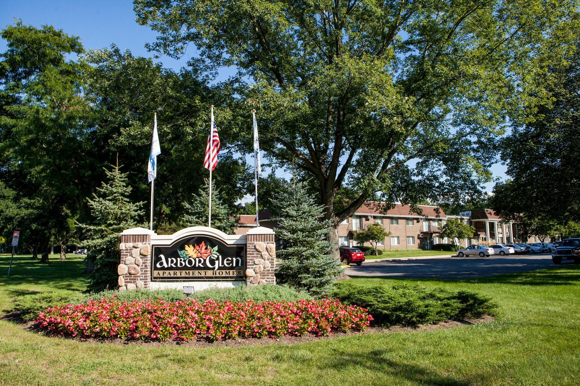 Sign for Autumn Glen apartments with flags and landscaping.
