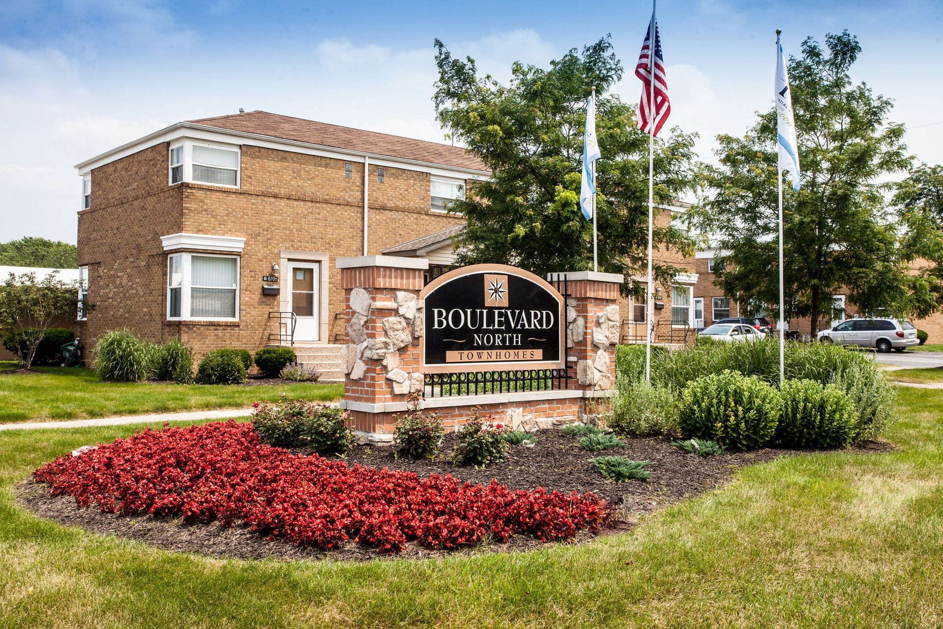 Boulevard apartments sign with brick building and landscaping; American flag and banner.