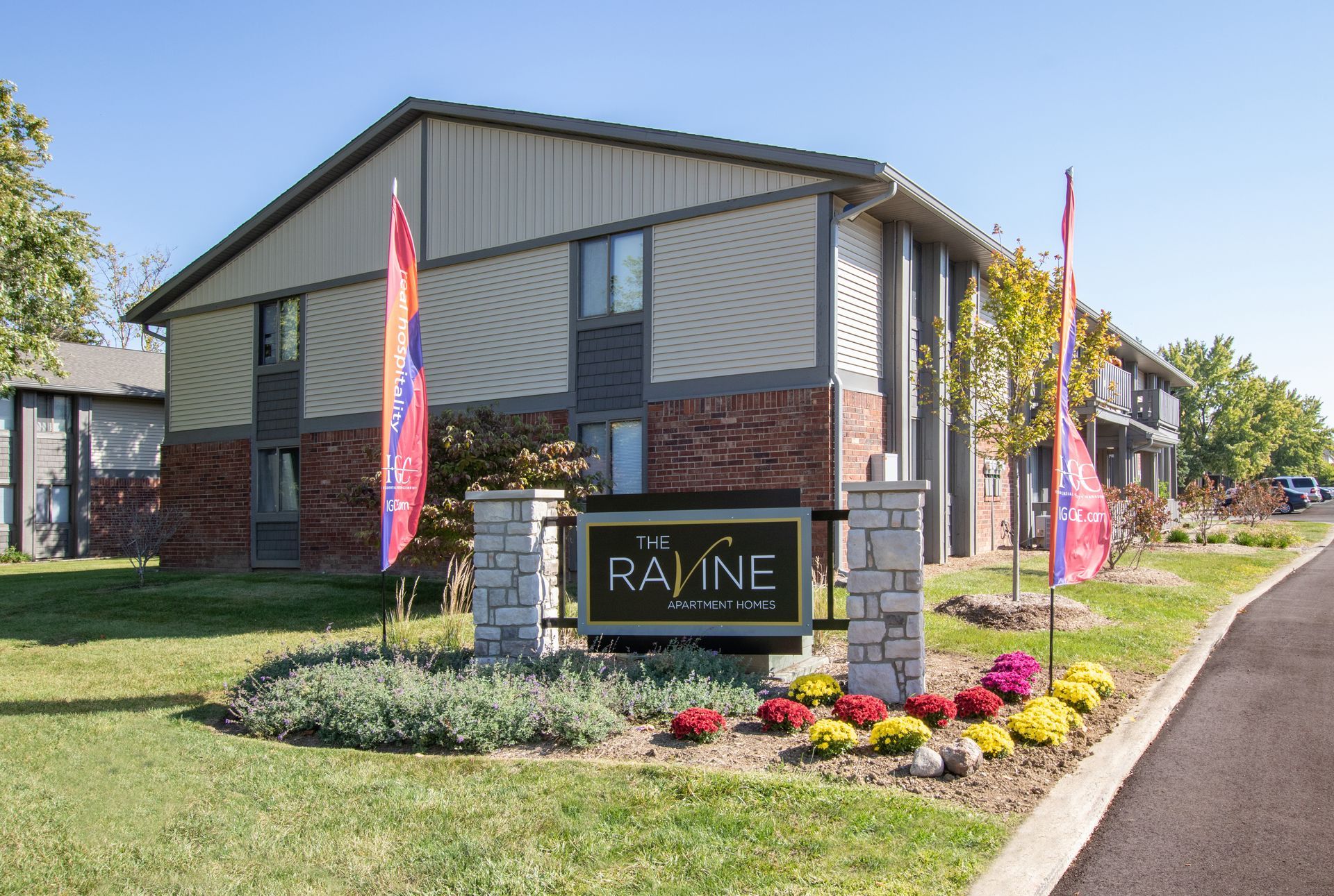 Ravine Apartments sign in front of a two-story building with flowers and landscaping.