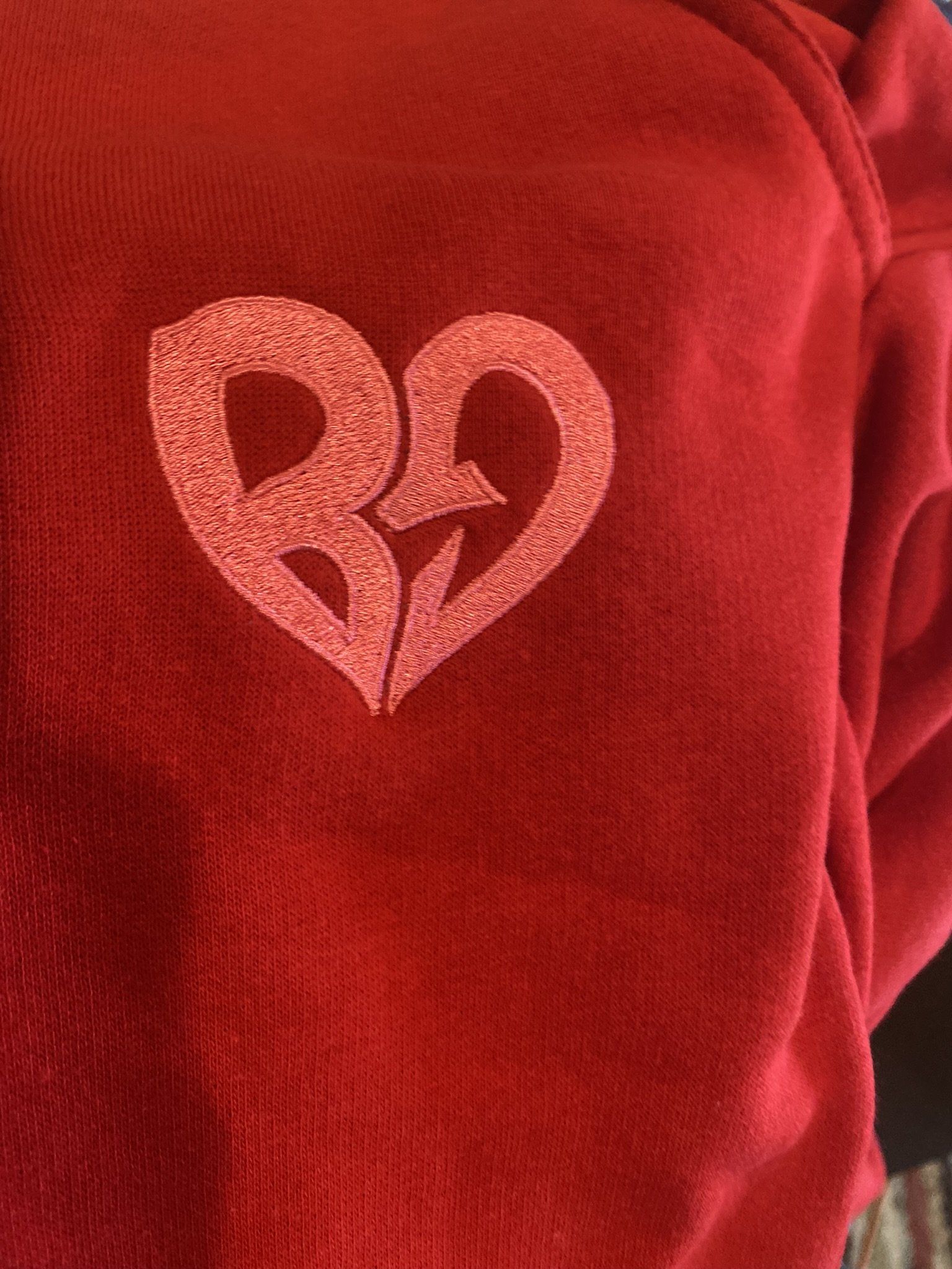 A red sweatshirt with a red heart embroidered on it.