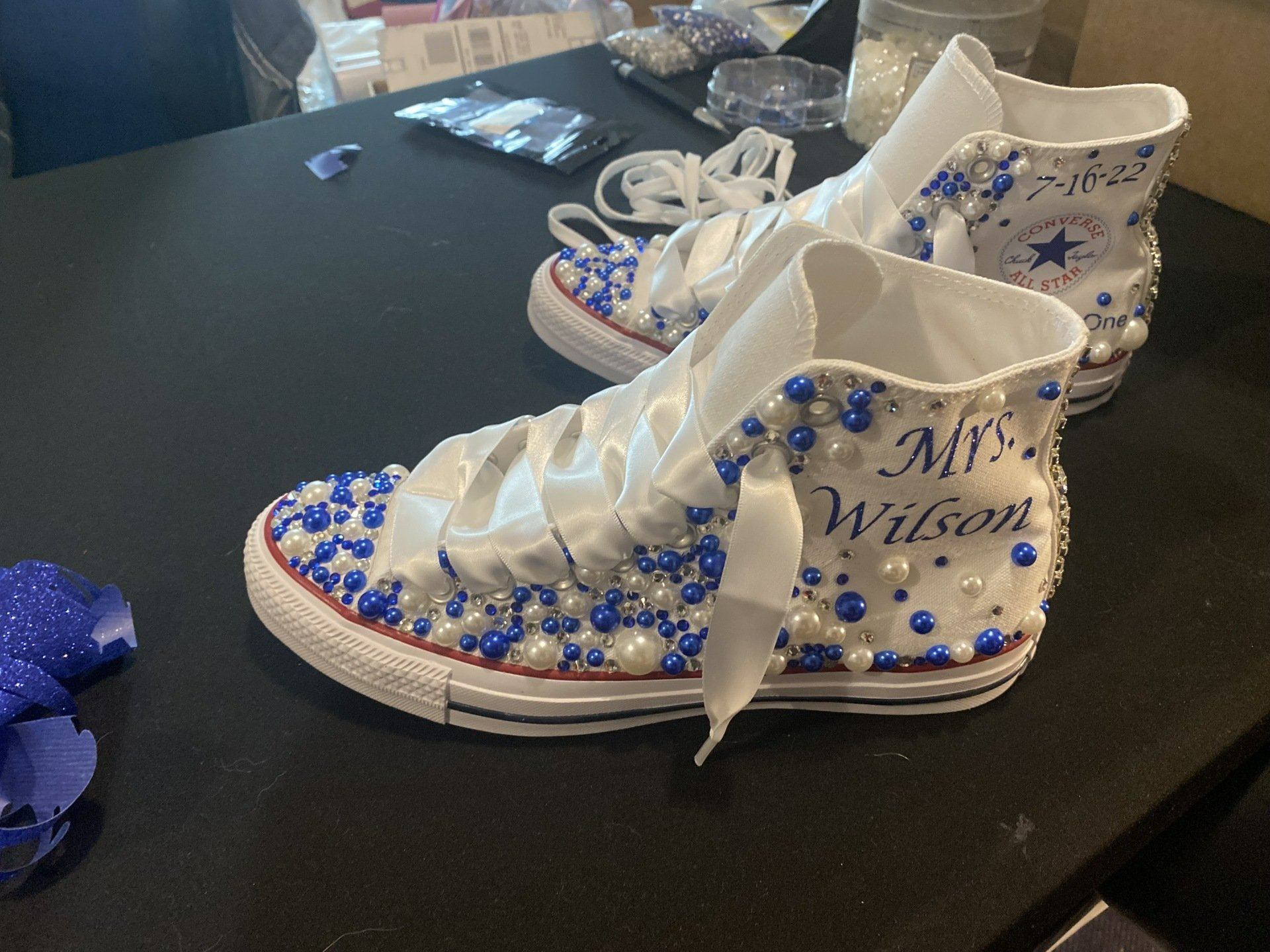 A pair of white shoes with blue beads and pearls on them