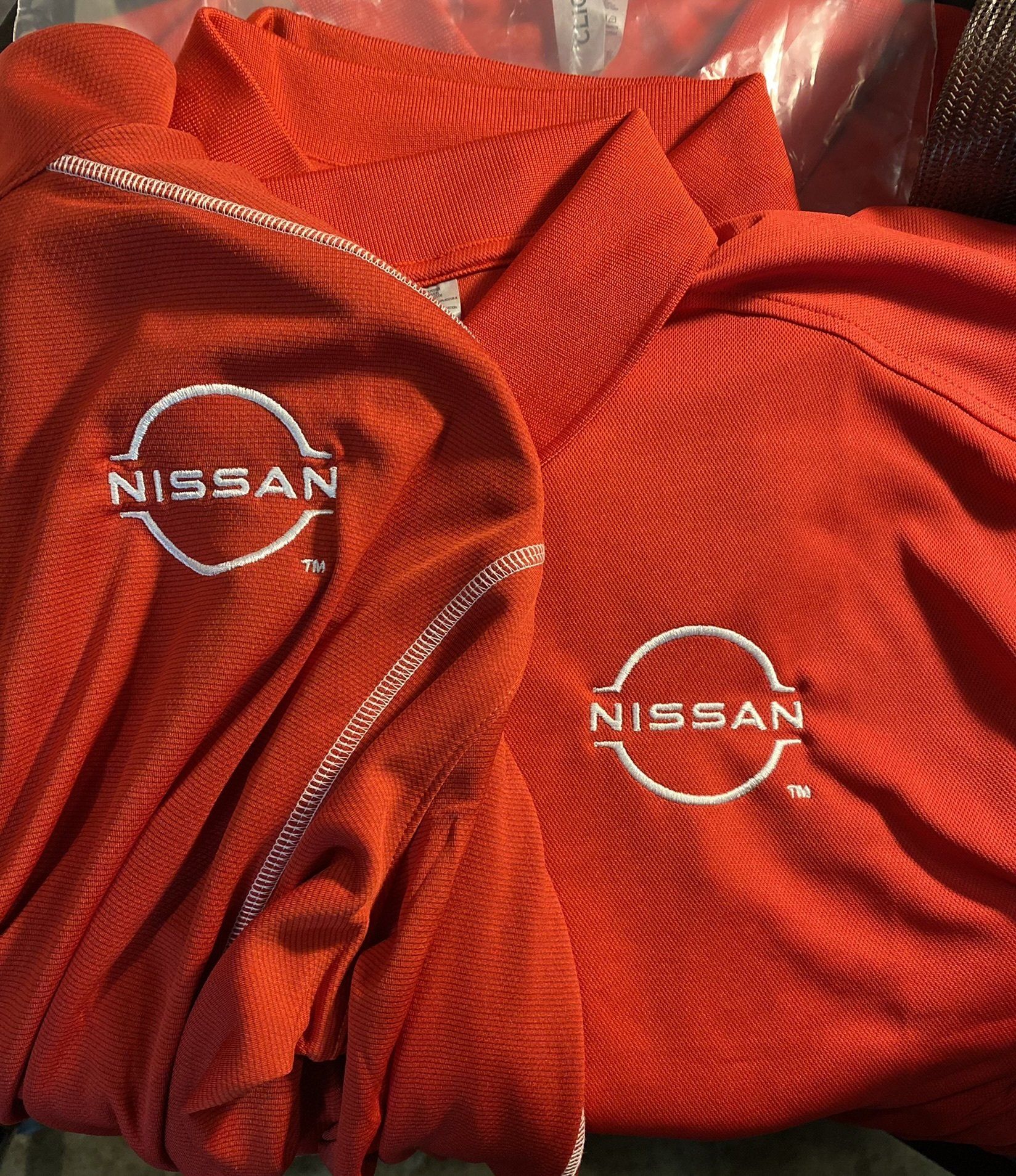 Two red nissan shirts are stacked on top of each other