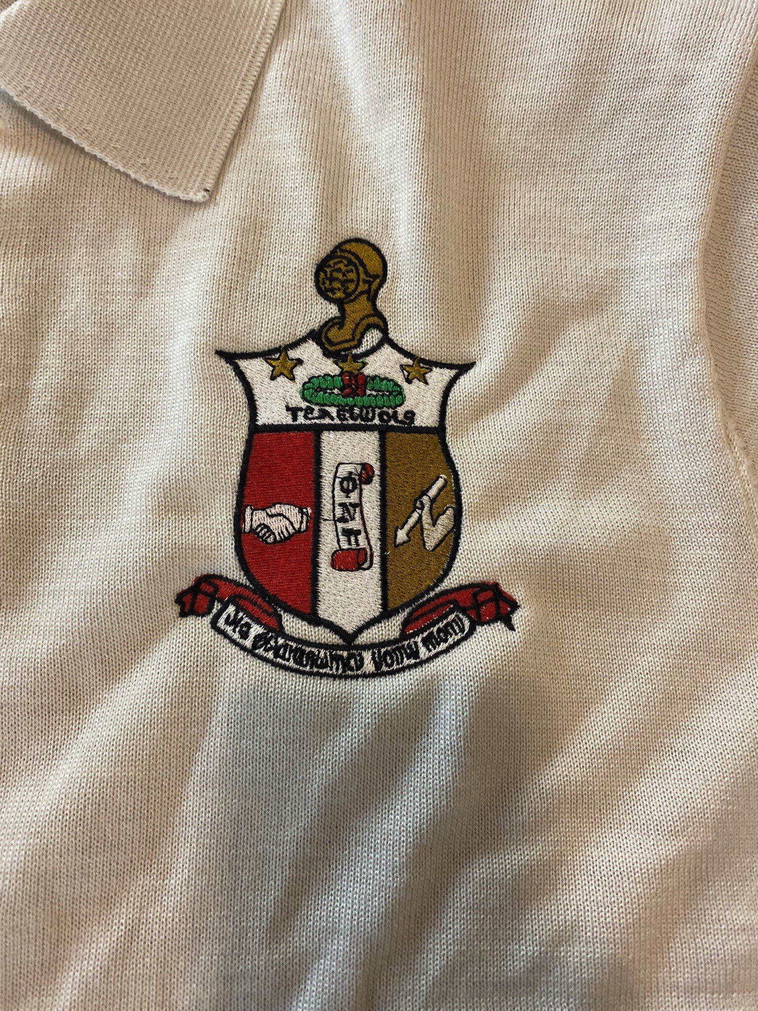 A close up of a white shirt with a coat of arms embroidered on it.