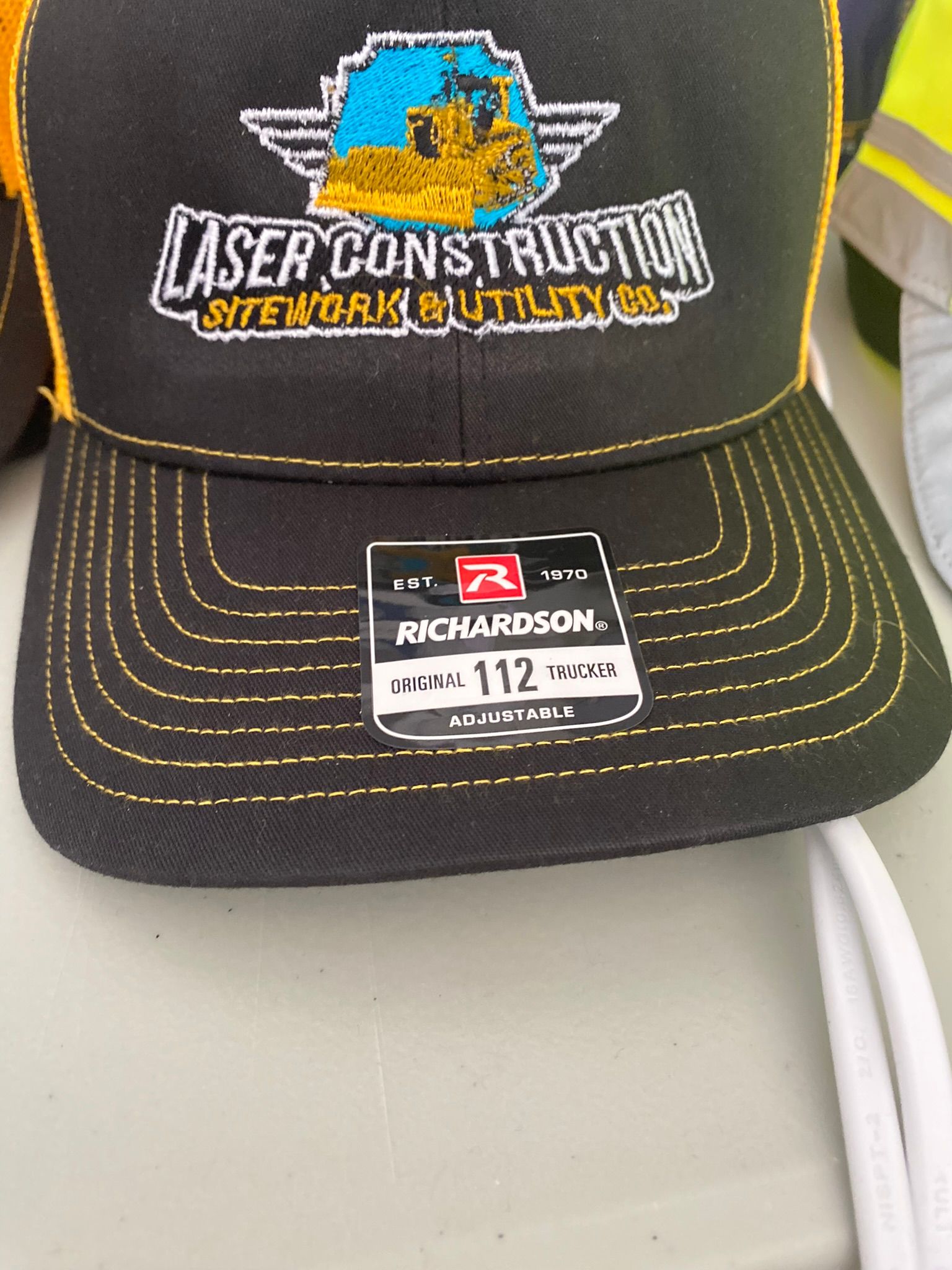 A black and yellow hat that says laser construction on it