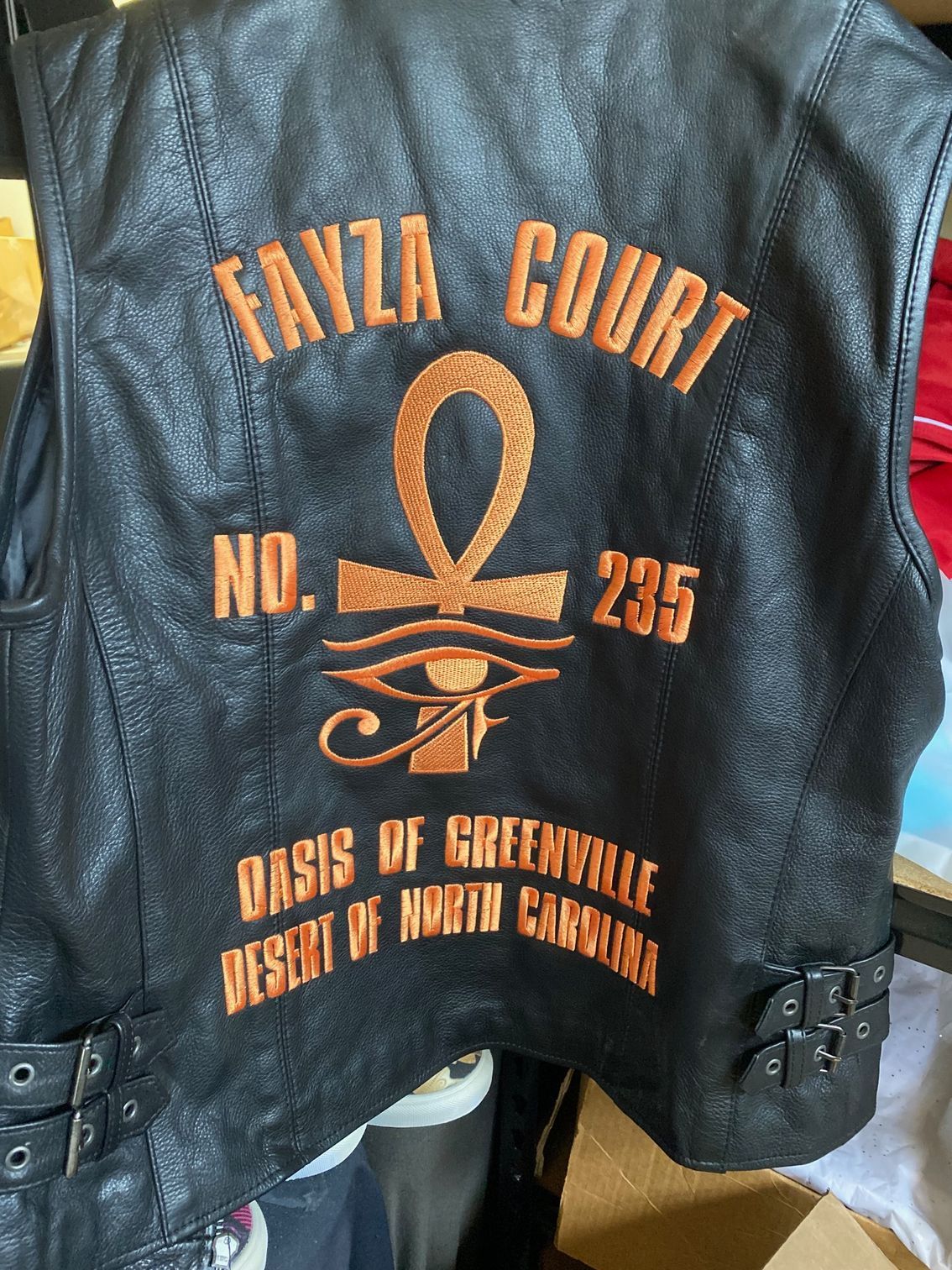 A black leather vest with the words fayza court on it