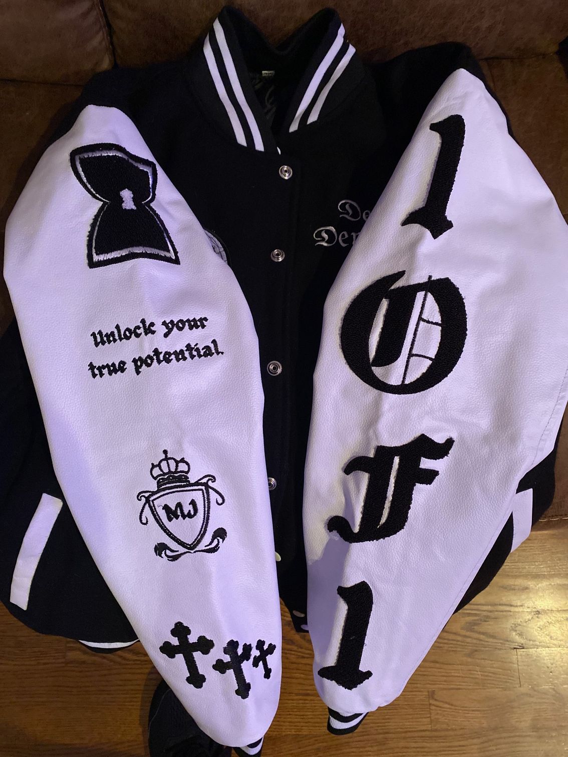 A black and white varsity jacket with the word fool on the sleeves