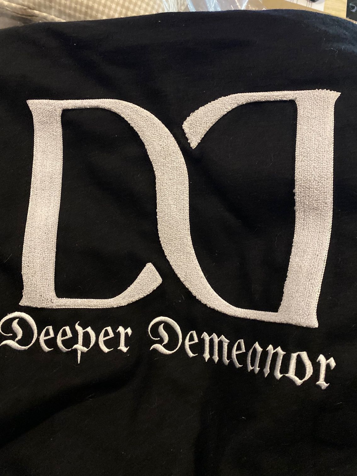 A close up of a black shirt that says deeper demeanor